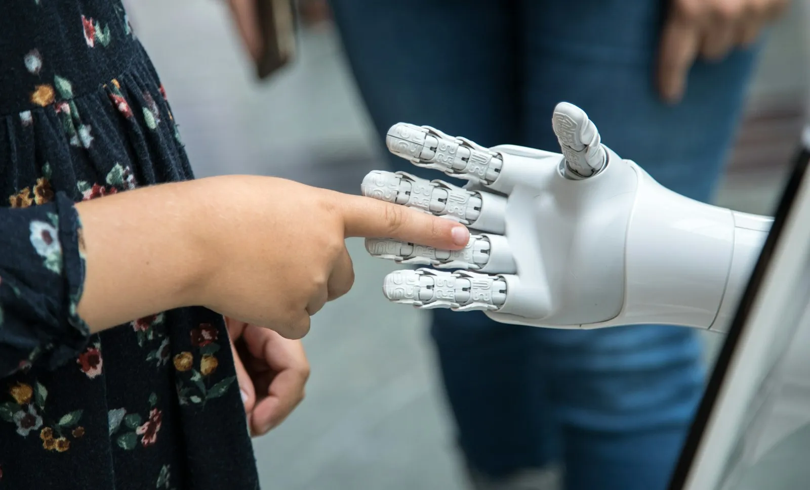 A person’s finger reaching out to touch a robot hand