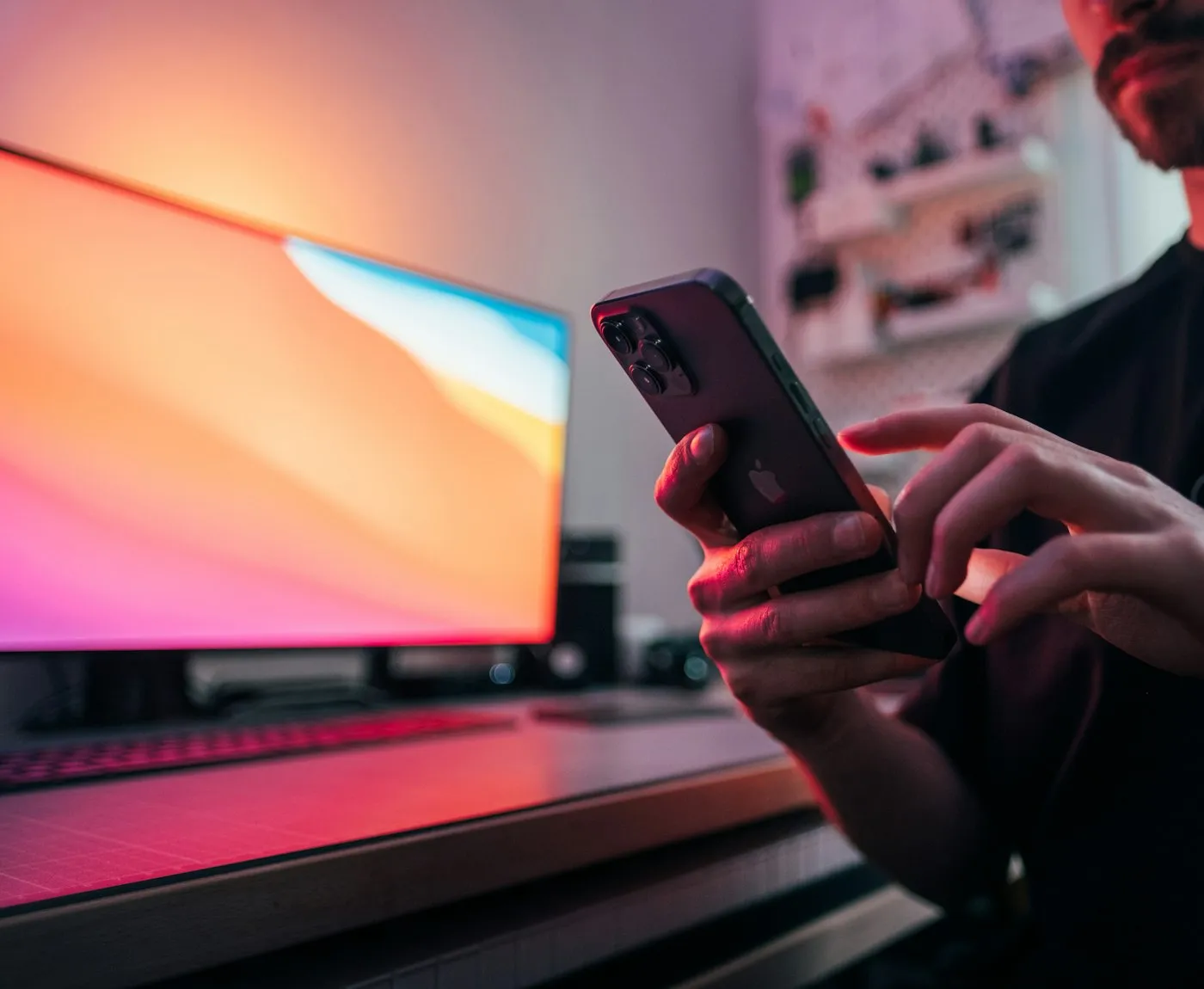 Developer holding a phone in front of a laptop with a bright screen