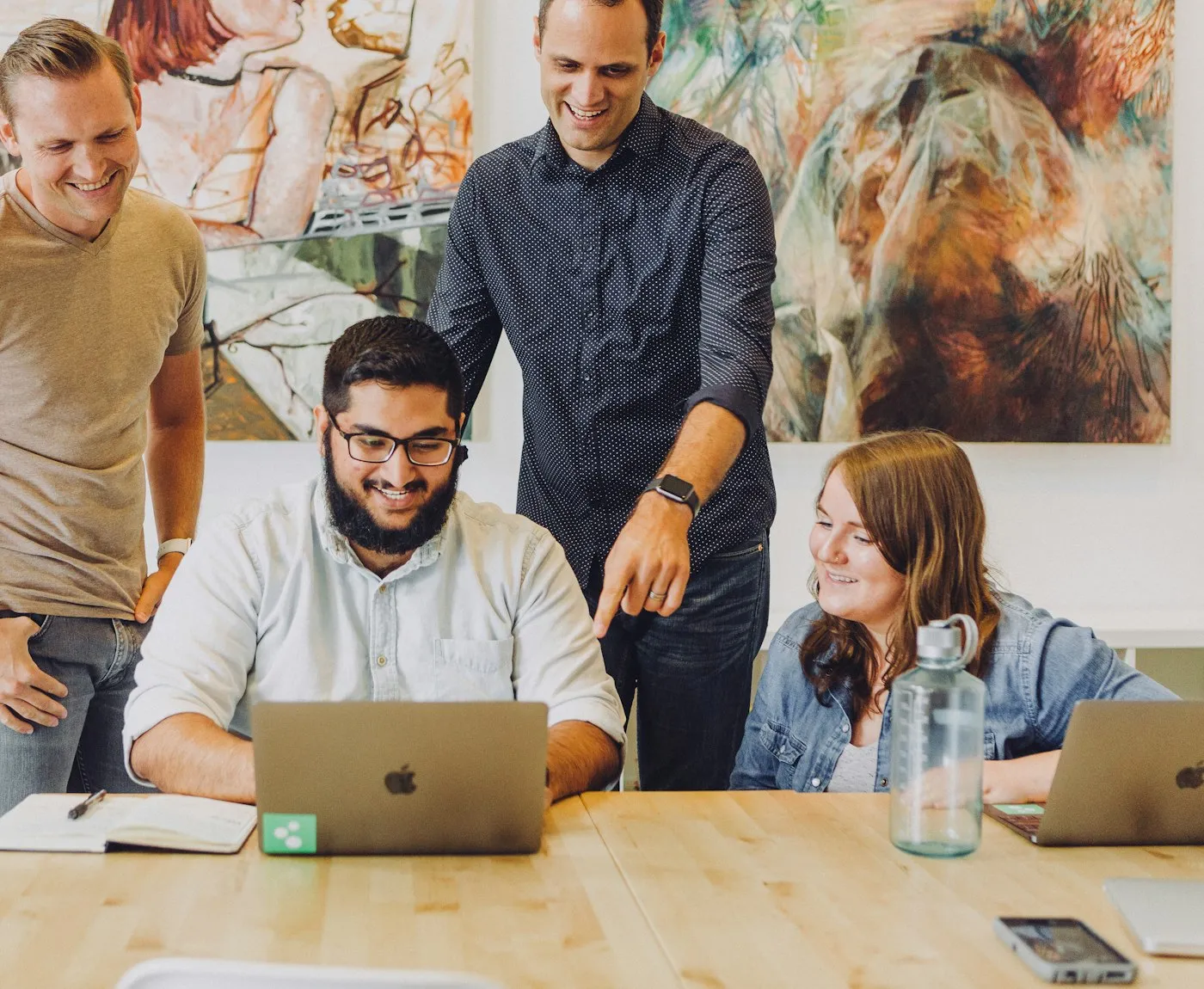Team reviewing work together around a laptop