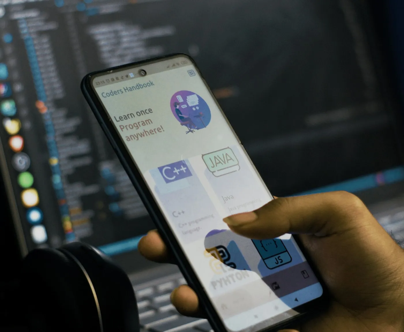 Developer holding a phone running an app in front of code